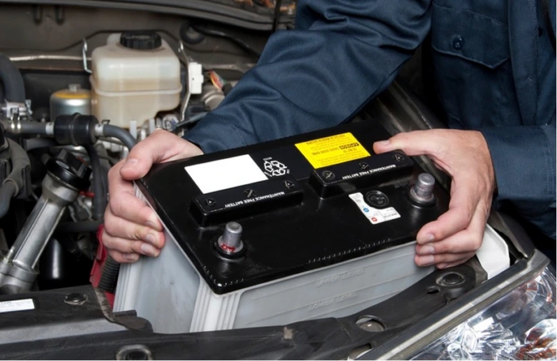Mechanik instaluje novou baterii do motorového prostoru.