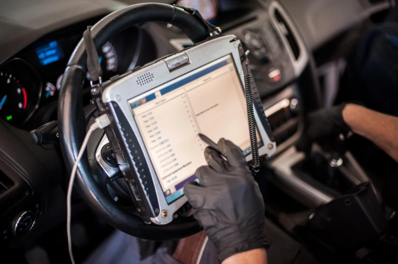 Technik diagnostiky převodovky v autě pomocí tabletu.