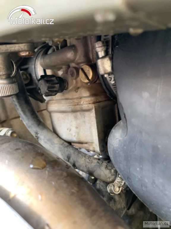 Detailní pohled na karburátor motocyklu s viditelnými nastaveními.