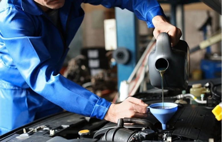 Mechanik nalévá olej do motora pomocí lejna.