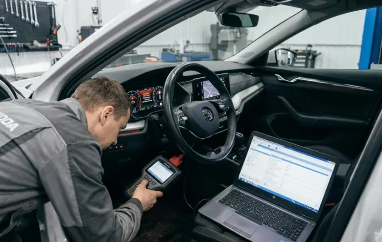 Mechanik diagnostika motoru pomocí skeneru a notebooku v autě.
