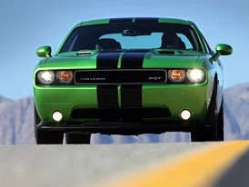 Zelený automobil Dodge Challenger na silnici s horami v pozadí.