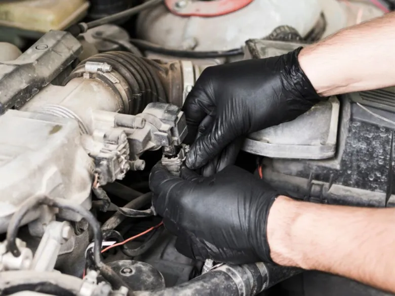 Mechanik opravuje součásti motoru vozu v prašném prostoru.
