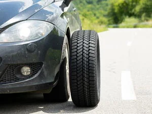 Automobil s odmontovaným kolem na silnici.