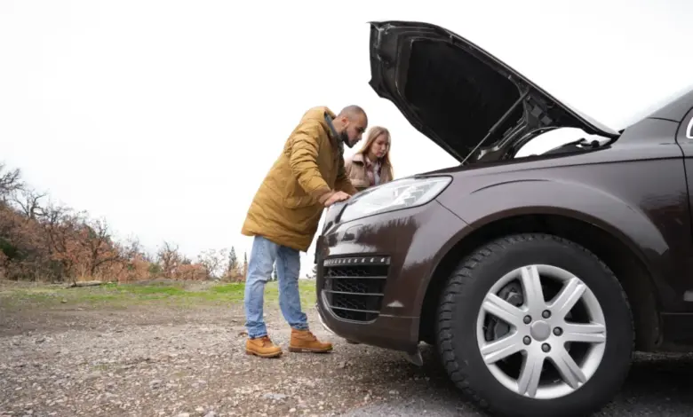 Muž a žena zkoumají motor pod kapotou auta na silnici.