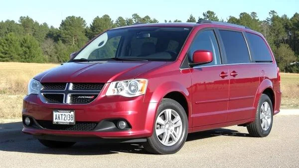 červený minivan Dodge Grand Caravan na asfaltu před stromy