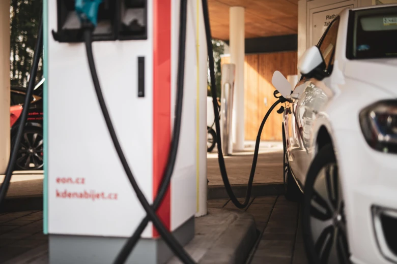 Bílé auto nabíjené na veřejné elektřinové stanici.