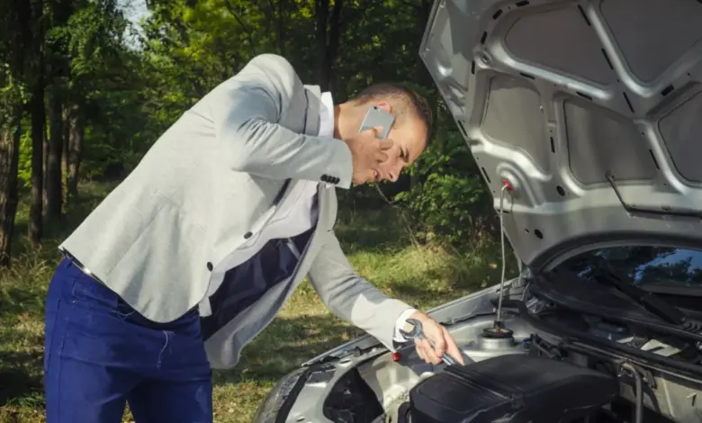 Muž opravuje motor auta venku a řeší problém s benzínem.
