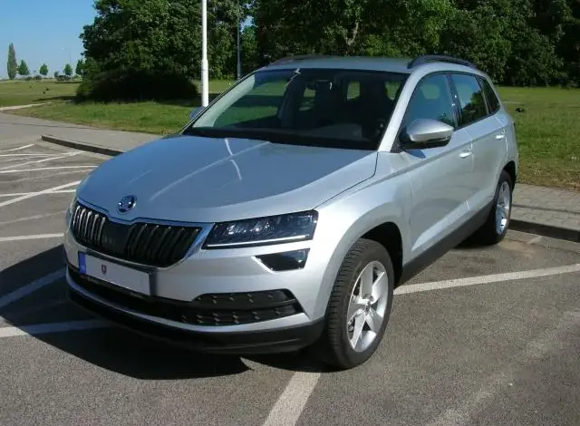 Stříbrný SUV Škoda Karoq zaparkovaný na asfaltovém parkovišti.