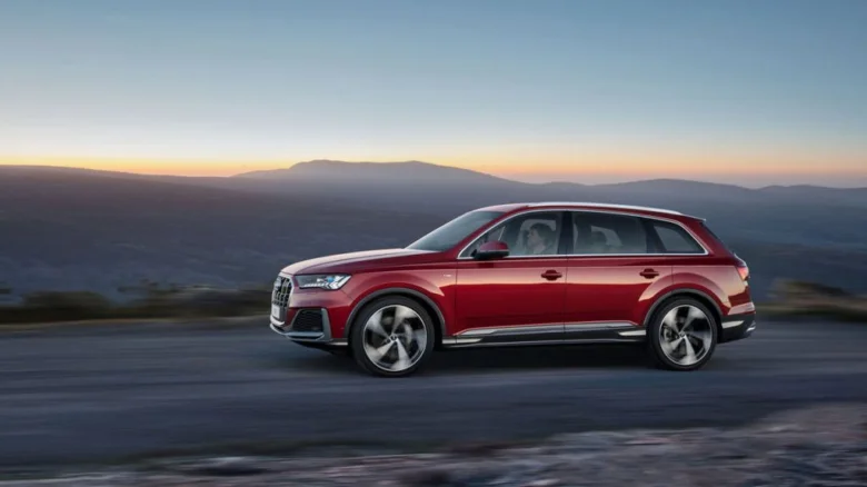 Červený automobil značky Audi jezdí po horské silnici.