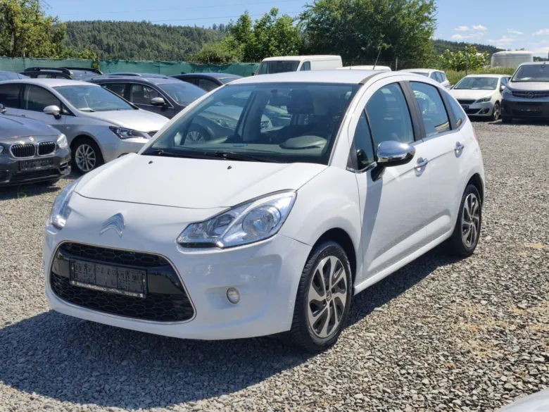 Bílý hatchback Citroën C3 zaparkovaný na štěrkové ploše.