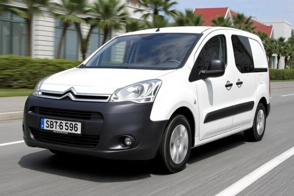 Bílý Citroen Berlingo jezdí po silnici.