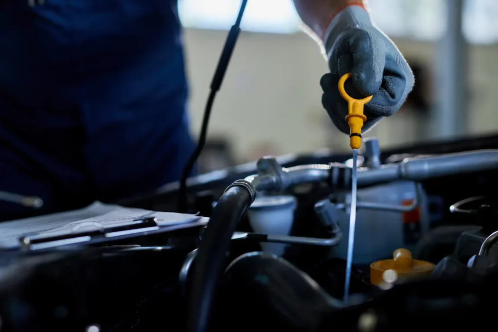 Mechanik kontroluje hladinu oleje v motoru pomocí lžíce.