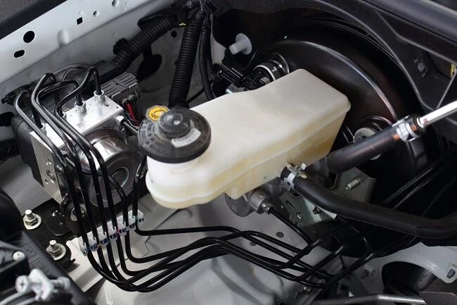 Brzdný čerpadlo s ABS v motorovém prostoru automobilu.
