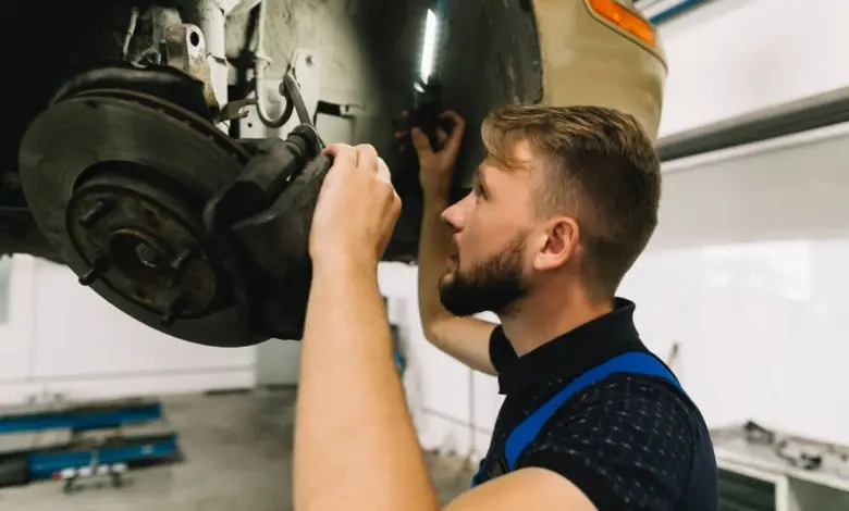 Mechanik opravuje brzdný systém vozu v dílně.