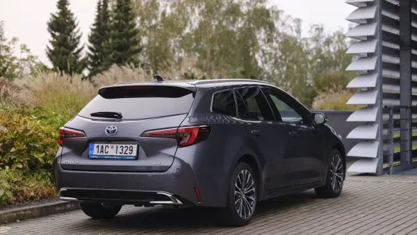 Šedý kombi Toyota zaparkovaný na asfaltu poblíž zeleně.