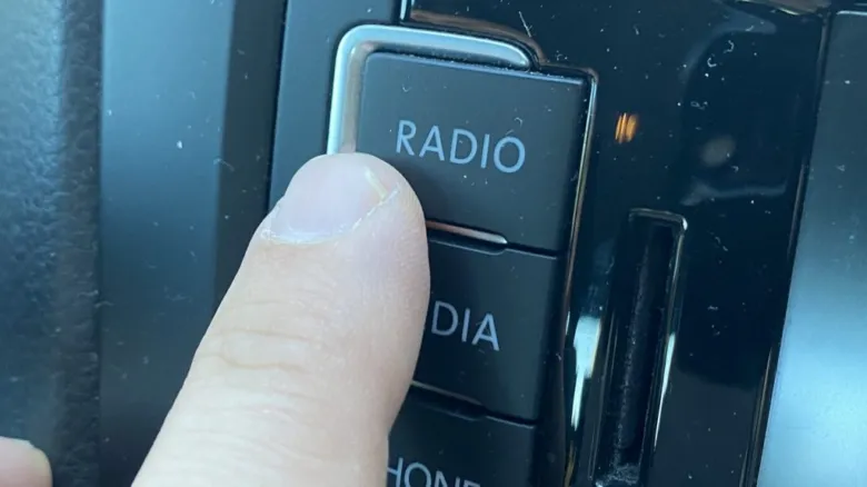 Prst tlačítko RADIO na autorádiu v autě.