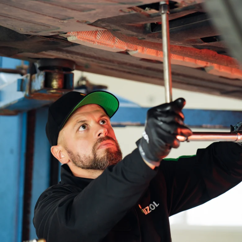 Mechanik kontroluje spodní část vozu v dílně.