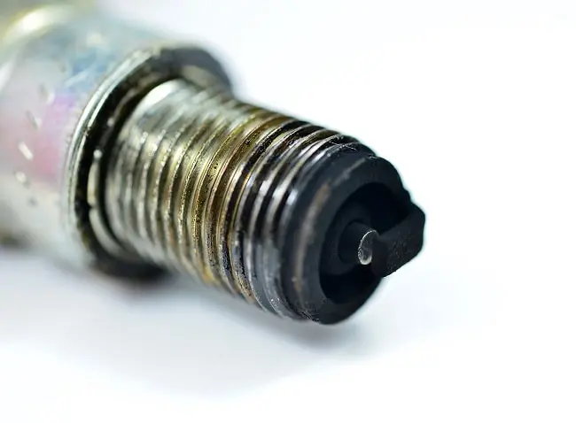 Použitý zapalovací svíčka s uhlíkovým usazením na elektrodách.