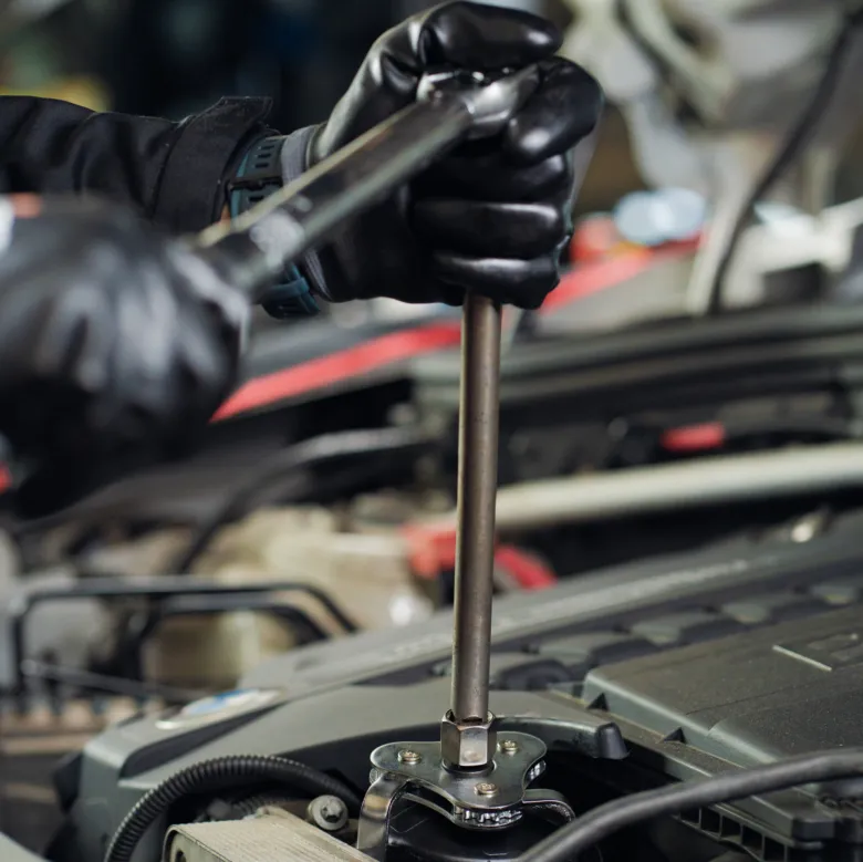 Mechanik s klíčem opravuje motor automobilu.