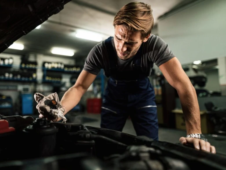 Mechanik čistí motor vozu v garáži.