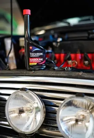 Fľaše s aditivem pro benzínové motory na chladiči starého auta.