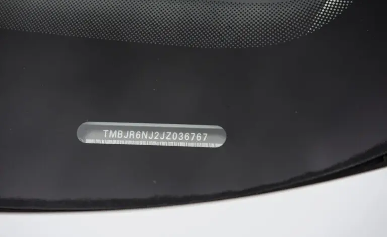Blízký záběr na číslo šasi (VIN) uvnitř čelního skla automobilu.