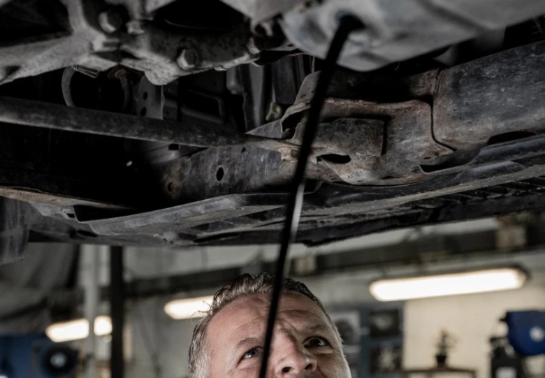 Mechanik vypouští olej z podvozku vozu v dílně