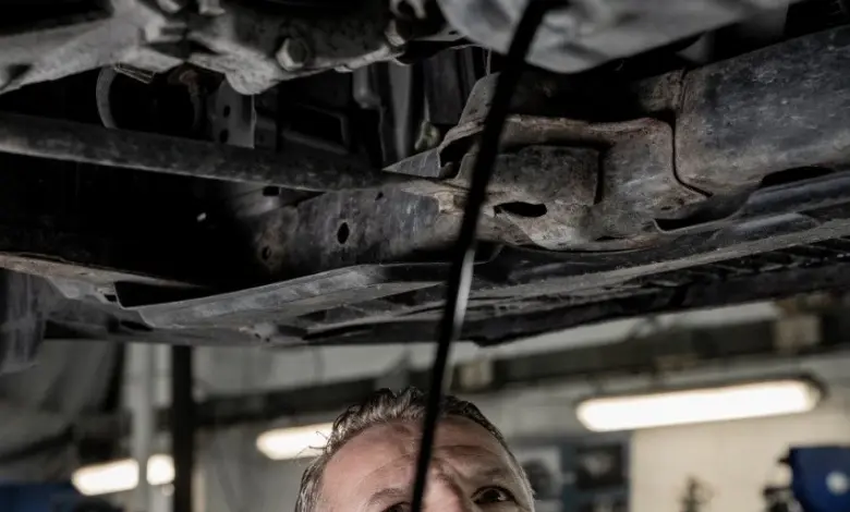Mechanik pod autem při výměně oleje v dílně.