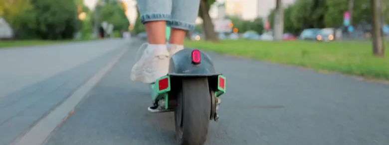 Elektrická koloběžka jezdí po silnici s viditelným zadním kolem.