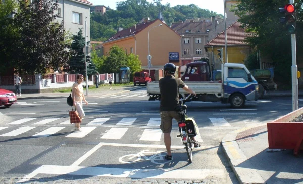 Cyklista čeká na průjezd křižovatkou s chodci.