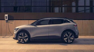 Stříbrné elektrické auto nabíjené u zdi.