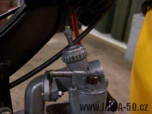 Karburátor na krovinovači s viditelnými šrouby pro seřízení.