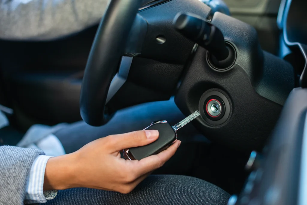 Ruka vkládá klíč do zapalovače automobilu u volantu.