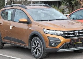Oranžové SUV auto zaparkované na asfaltu s viditelným předním nárazníkem.