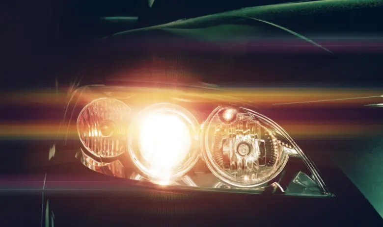 Zapnuté světlomety automobilu s jasným světlem v noci.