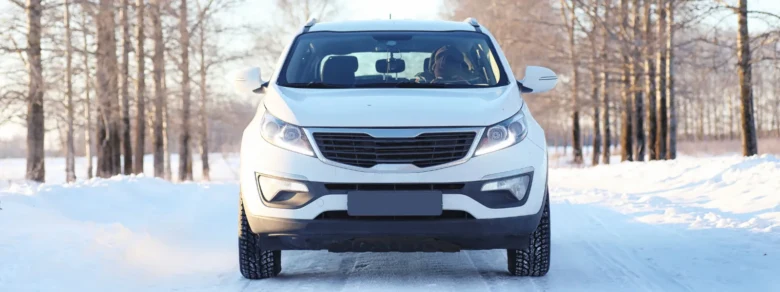 Bílý automobil v zimě na sněžné cestě ukazuje startování auta za chladu.