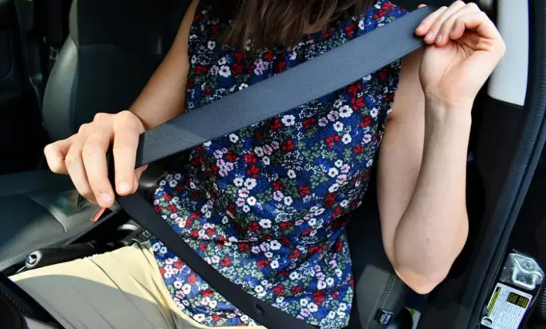 Žena v autě drží bezpečnostní pás před zapnutím.
