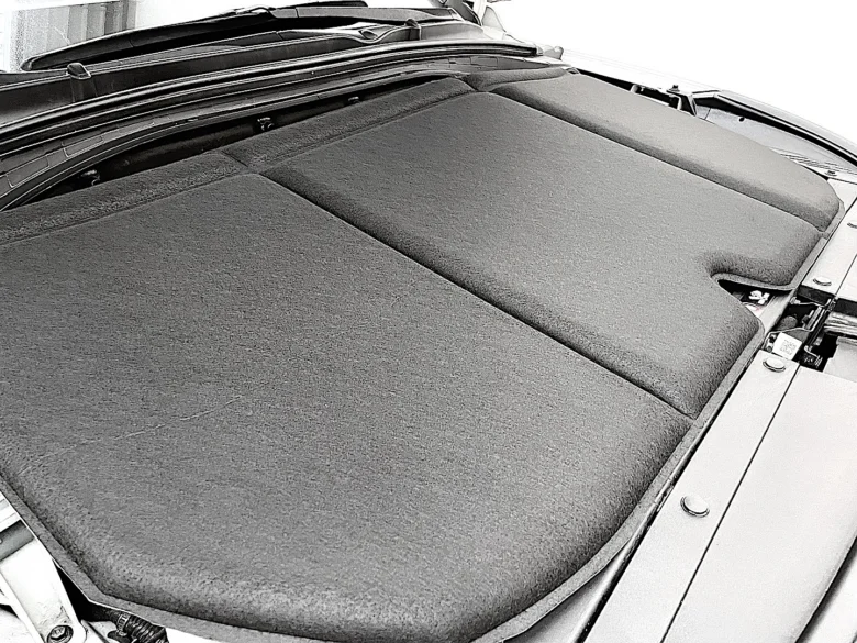 Zvuková izolace motorového prostoru s tmavým materiálem.