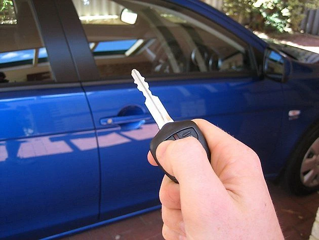 Ruka drží klíč k autu před modrým VW.