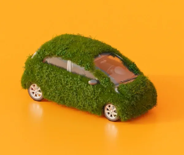 Model auta pokrytého trávou na oranžovém pozadí.