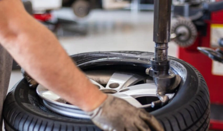 Mechanik montuje pneumatiku na ráfek v dílně