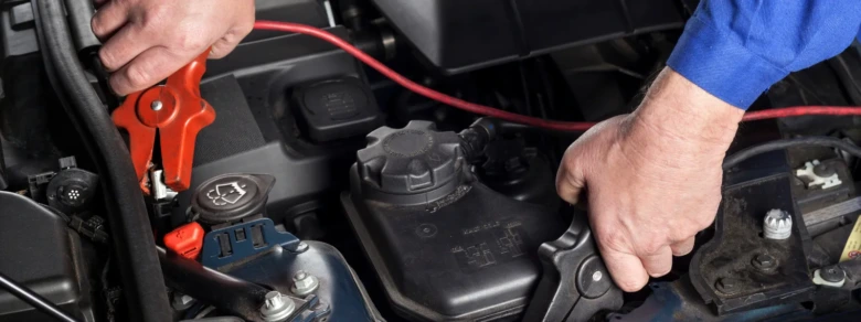 Mechanik připojuje kabely k baterii pro startování dieselu.