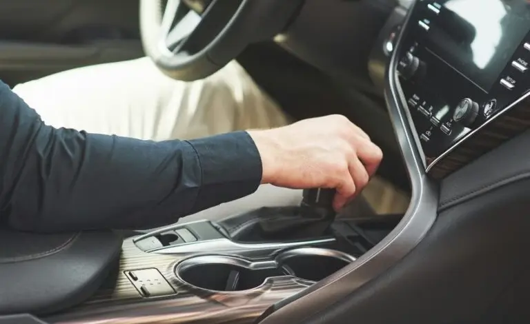 Ruka řidiče přepíná převodovku v automobilu.