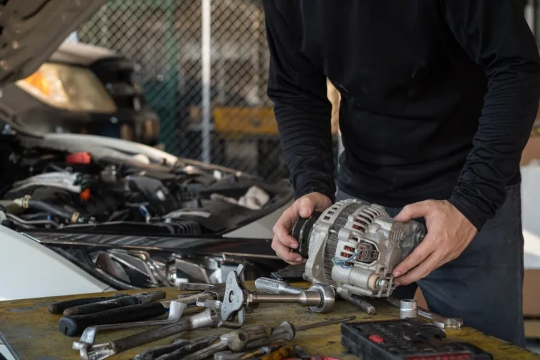 Mechanik drží automobilový střídač u motoru vozu.