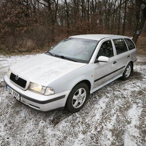 Bílá Škoda Octavia kombi zaparkovaná na sněhu v lese.