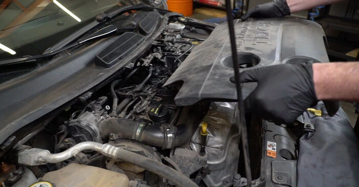 Mechanik odstraňuje kryt motoru u Fordu pro výměnu řemene.