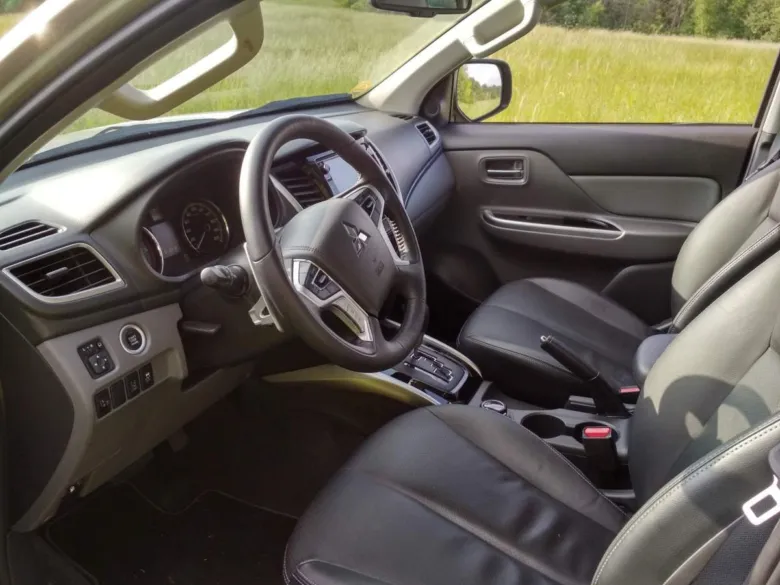 Vnitřek vozu Mitsubishi L200 s černými sedadly.