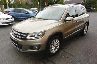 Zlatý Volkswagen Tiguan zaparkovaný na asfaltovém parkovišti.