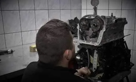 Mechanik pracuje na výměně motoru v dílně s nástroji.